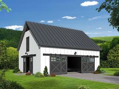 a white barn with a black roof and two garage doors on the side of it