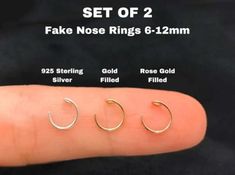 three pairs of fake nose rings are shown in different sizes and colors on the finger