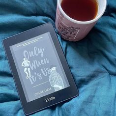 a cup of tea and a kindle on a bed