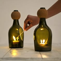 two green bottles with candles in them sitting on a table