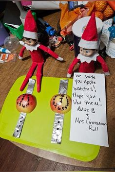 two elfs on a table with a note attached to them