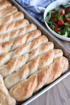 a pan filled with bread next to a bowl of salad