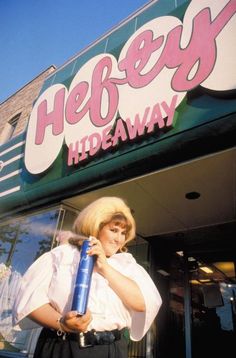 a woman standing in front of a store holding a large blue item with the words hey hideaway on it