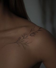 the back of a woman's shoulder with a flower tattoo on her left side