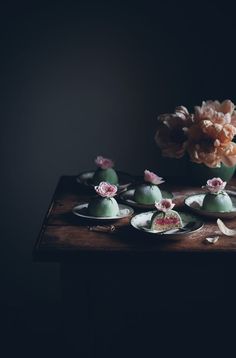 there are many small desserts on the table with flowers in the vase behind them