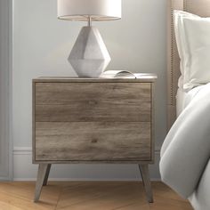 a nightstand with a lamp on it next to a bed