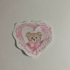 a heart shaped sticker with a teddy bear on it's back and pink ink