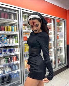 a woman in a costume is standing next to a refrigerator full of drinks and sodas