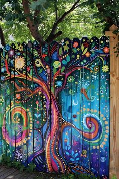 a colorful tree painted on the side of a fence