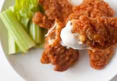 a white plate topped with meat covered in sauce next to celery and lettuce