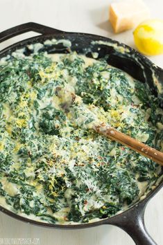 spinach and cheese in a skillet with a wooden spoon