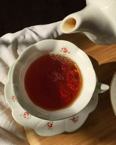 there is a bowl of soup on the table next to a cup and saucer