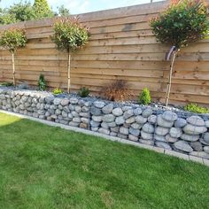 a stone wall in front of a wooden fence