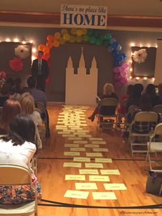 a room full of people sitting and standing in front of a sign that says home