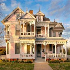 an old victorian style house with white trim and pink paint on the front door, windows and balconies