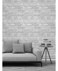 a couch sitting in front of a white brick wall with pillows on top of it