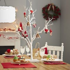 a christmas tree with ornaments on it sitting in front of a table set for two