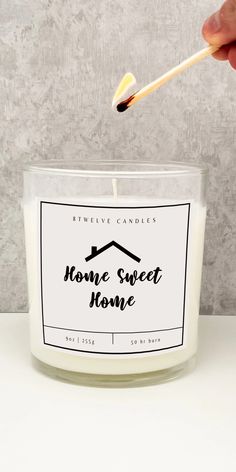 someone is holding a wooden spoon over a candle with the words home sweet home on it