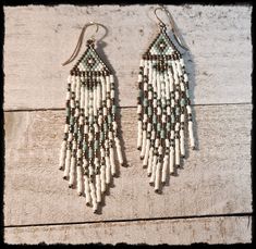 two pairs of beaded earrings on top of a wooden table next to each other