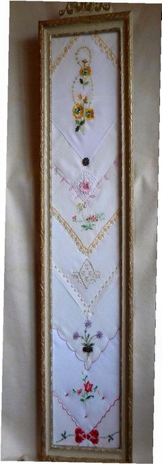 an embroidered wall hanging in a frame with flowers and hearts on the bottom half of it