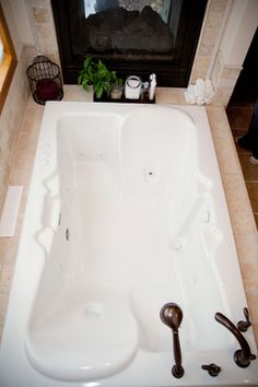 a large white bath tub sitting next to a fire place