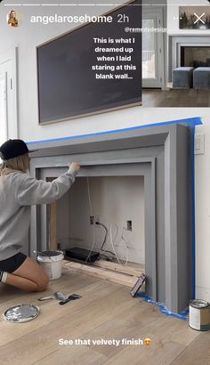 a woman kneeling down to paint a fireplace