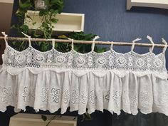 a white lace curtain hanging from a wooden rod