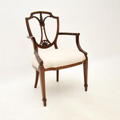 an antique chair with white upholstered fabric on the back and armrests