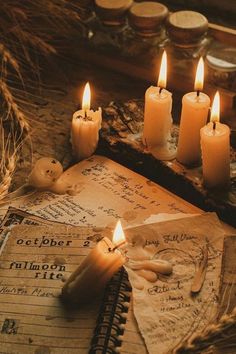 some candles are sitting on top of an old book with writing and other items around it