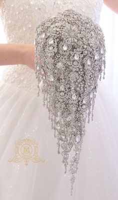 a woman in a white wedding dress is holding a crystal beaded bouquet