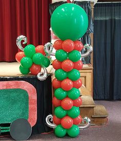 a balloon decoration is on display in front of a red carpeted room with curtains