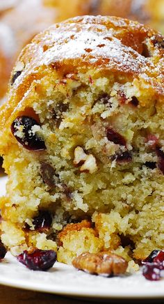 a close up of a muffin on a plate with cranberries and nuts