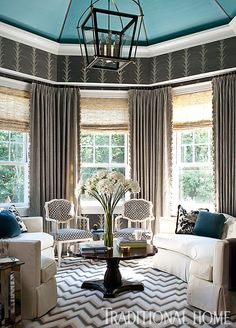 a living room filled with white couches and chairs under a blue sky light fixture