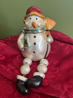 a snowman figurine sitting on top of a red blanket