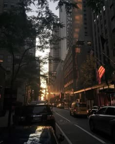 the sun is shining down on a city street with tall buildings and cars in traffic