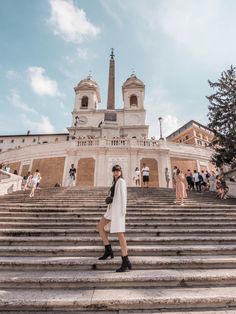 a woman is walking down some steps in front of a building with a steeple