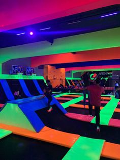 children playing on an indoor trampoline course in a gym with neon colored walls