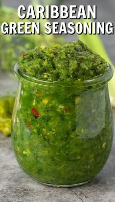 a jar filled with green seasoning sitting on top of a table next to vegetables