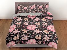 a black and pink floral bed spread with matching pillowcases on a wooden floor