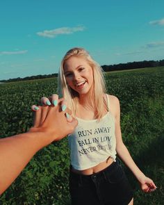 a woman is holding her hand out to another person in the middle of a field