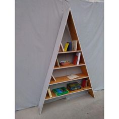 a triangle shaped book shelf with books on the bottom and shelves below it, in front of a white backdrop