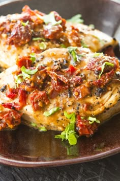 two pieces of chicken covered in sauce on a plate next to a fork and knife