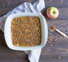 an apple and cinnamon bread in a white casserole dish on a wooden table