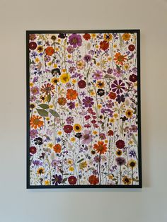 a painting on the wall with flowers painted on it and framed in black wood frame