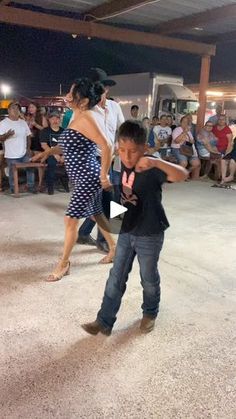 a young boy and woman dancing in front of an audience