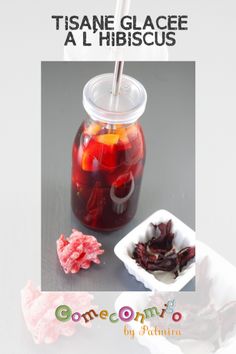 a jar filled with liquid next to a bowl of dried fruit on top of a table