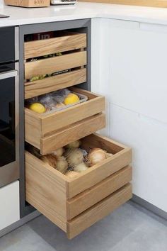 an open drawer in the middle of a kitchen with vegetables and fruit inside it,