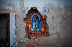 an old wall with a statue on it and candles in front of the window that is lit