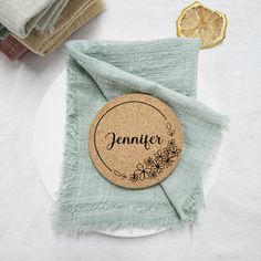 a white plate topped with a green napkin and a wooden name tag on top of it