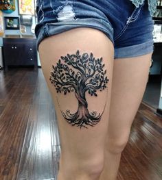 a woman's leg with a tree tattoo on it, and the bottom part of her thigh